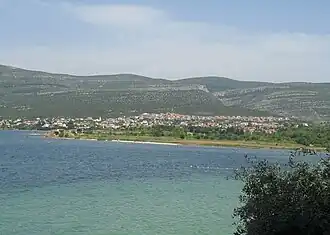 A body of water with a bay and mountains in the distance.
