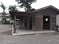 A white horse outside a wooden stable.