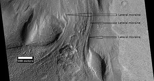 Material flowing through a crater rim. HiRISE image. Lateral moraines are labeled.