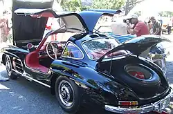 A black coupé with its bonnet, both doors, and boot open