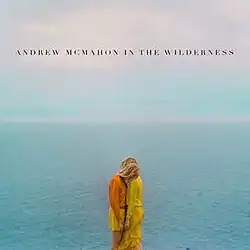 Two women standing close to each over with an ocean behind them