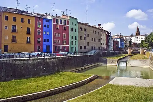 A row of 3-4 story rowhouse with a river and a bridge