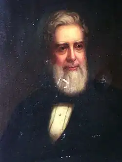 A slightly distressed oil painting of an old bearded man in a dark suit