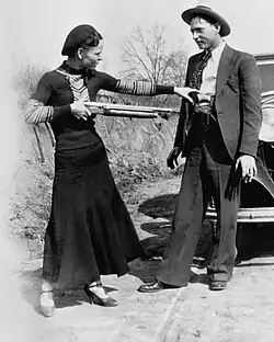 Bonnie with a shotgun reaches for officer Persell's pistol in Clyde's waistband.[3]