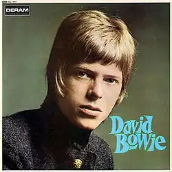 A young man in a mod haircut wearing a high-collared jacket.