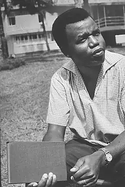 Achebe in blue cap at lectern