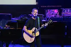 An older man playing an acoustic guitar
