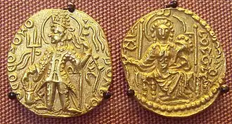 Coin of Vasudeva II. The name of the ruler appears vertically next to his left arm in Gupta script: Vā-su.