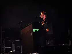 Martin performing with his microphone and piano, wearing a black outfit