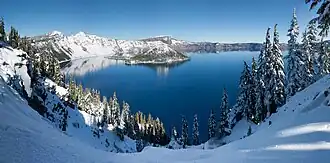 A panorama shot shows Crater Lake in the winter season. Its surroundings are covered in snow