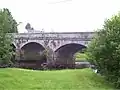 A grey road bridge with three arches