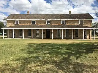 A portion of the parade ground (bottom half) and the fort headquarters building (upper half)