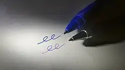 Picture of writing tips of a gel pen and a ballpoint pen lying on a piece of paper next to lines created by each pen.