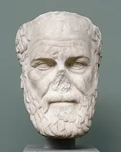 Head of a bearded man, carved from white stone. The nose is broken off.