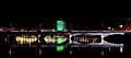 a night-time view of a five-span road bridge, with a building, lit in green, in the background