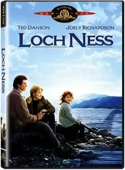 A man, a woman, and a child, sitting by the rocky shore of a lake.