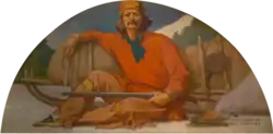 Man dressed as voyageur fur trader, holding rifle while sitting and leaning on sled loaded with gear. Campfire is to his right. In the background are trees.