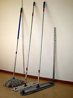 Three mops leaning against a wall