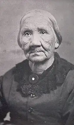 Mother Solomon with short hair worn back wearing a buttoned top and a collaret.