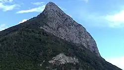 End of a mountain ridge seen in profile overlooking a wooded area.