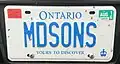 Personalized plate (front) attached to a pickup truck. As a pickup truck it should otherwise bear a black on white commercial plate, but the personalized plate is blue on white. Validation and "personal use" tags are affixed to the front plate, as in the case of other pickups.