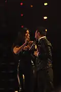 A man and a woman dressed in black performing on a stage.