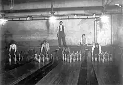 Boys setting up pins in a bowling alley