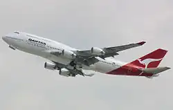 Side view of four-engine jet climbing in the sky.
