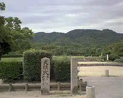 Modern stele in front of a park-like area.
