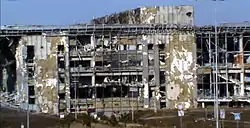 A large multi-story structure, its windows and cladding shattered to expose its concrete and steel superstructure.