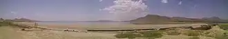 A panoramic view of a desert landscape with a body of water in the distance.