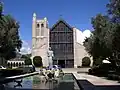 View of St. Andrew's statue, pool, olive trees, and front entrance