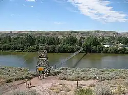 A suspension bridge crosses a wide river.