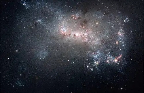 Image 22 NGC 4449 Photograph: NASA, ESA, A. Aloisi (STScI/ESA), and The Hubble Heritage (STScI/AURA)-ESA/Hubble Collaboration An image of NGC 4449, highlighting its qualities as a starburst galaxy. NGC 4449, an irregular galaxy in the constellation Canes Venatici located about 12 million light years from Earth, has a rate of star formation twice that of the Milky Way's satellite galaxy, the Large Magellanic Cloud. Interactions with nearby galaxies are thought to have influenced this star formation. More selected pictures