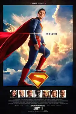 Superman in his blue and red costume stands atop the Superman "S" emblem in front of a sky backdrop. The tagline "It Begins" is to his right, with portraits of additional characters below.