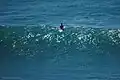 Surfer sitting on his board, thereby resting his back.