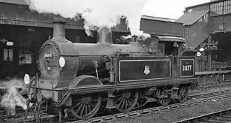 A black-and-white photograph of a tank engine at a station