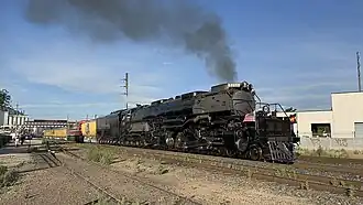 An articulated steam locomotive with a 4-8-8-4 wheel arrangement (four leading wheels, two separate sets of eight driving wheels, and four trailing wheels) and its tender