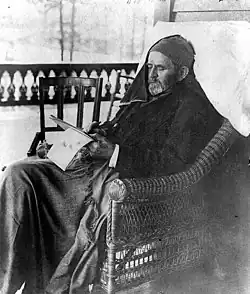 Grant sitting in a porch chair wrapped in blankets