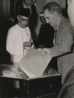 Two men removing documents from a metal box