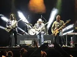 Four men perform music in front of an audience.