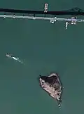 The Richmond–San Rafael Bridge (Interstate 580) alongside Red Rock Island and barges crossing San Pablo Bay.